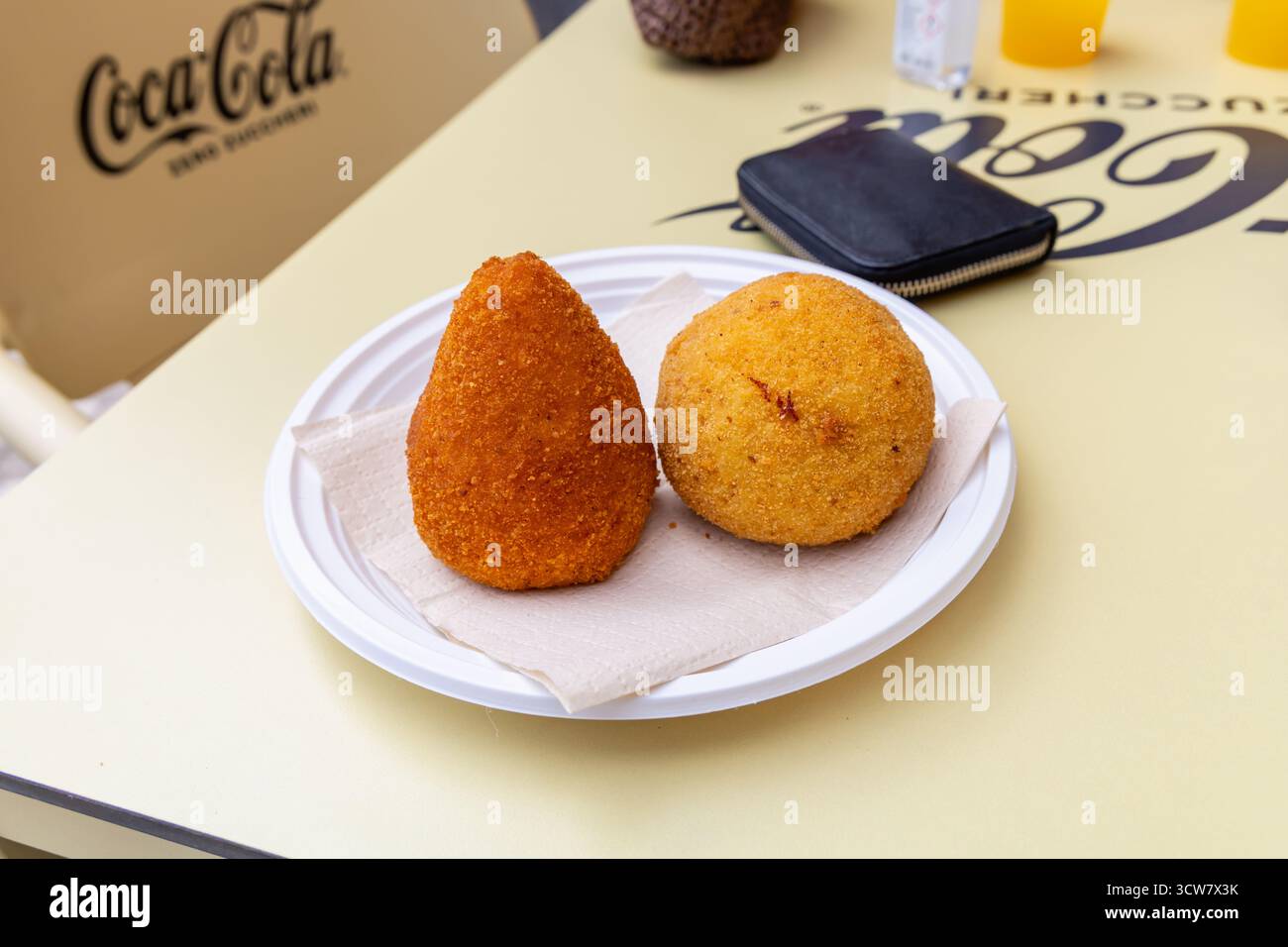 Traditionelle italienische Arancini-Reisbällchen mit Coca-Cola-Hintergrund. Noto, Italien - 9. Oktober 2025 Stockfoto
