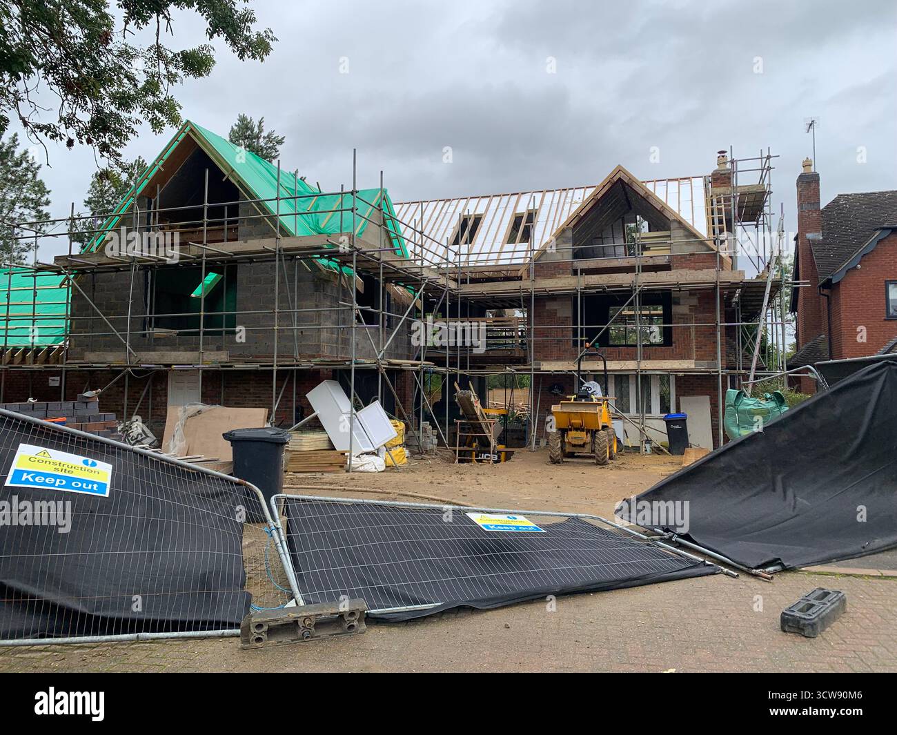Haus wird erweitert grüne Dachdeckenbauer Schutt große große Gerüste Schutt Windschadenpaneele freiliegende Balken beschädigte Abdeckung Wetter - Smartphone-aufgenommenes Stockfoto