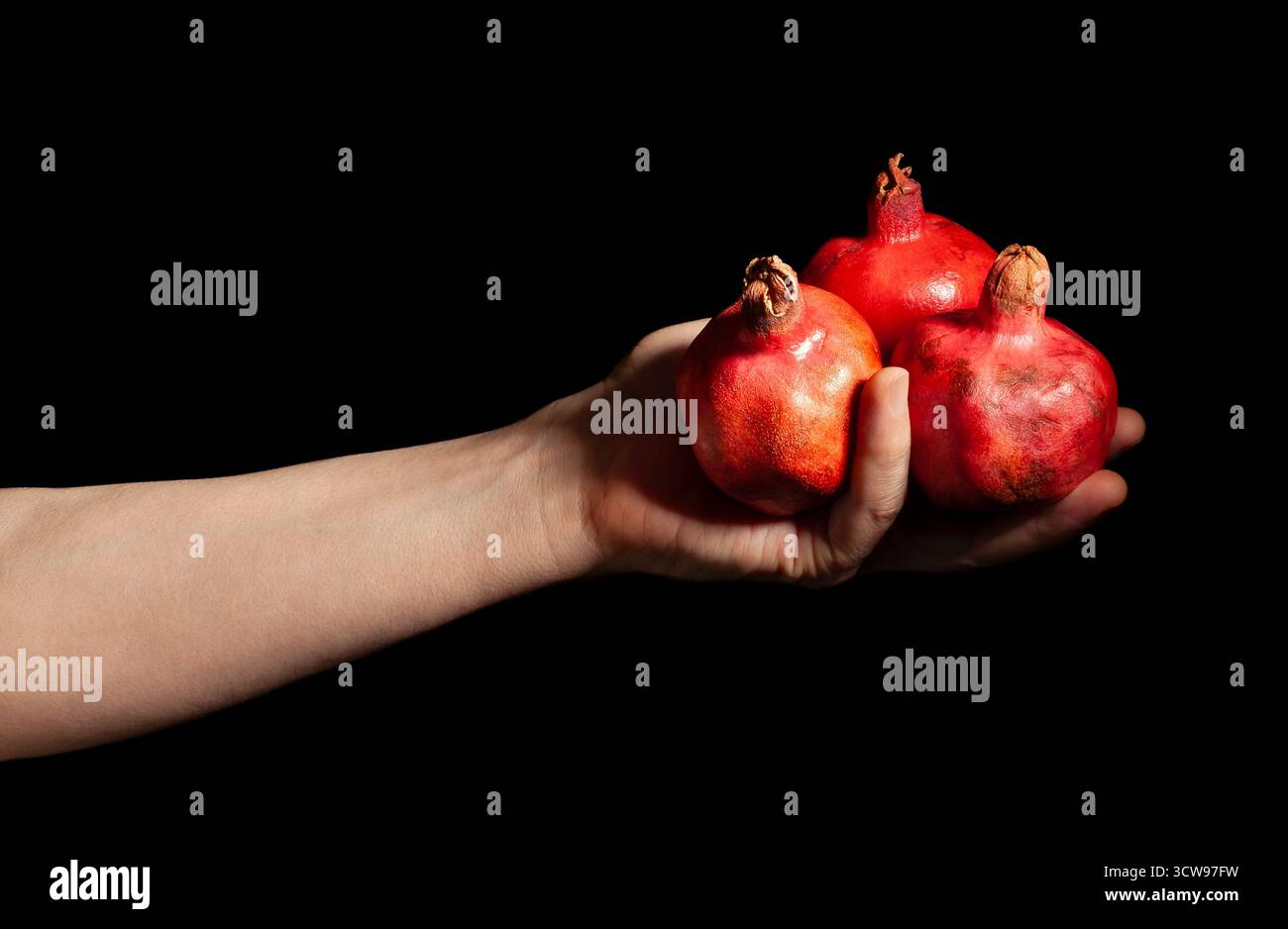Granatapfel in der Hand isoliert auf Schwarz Stockfoto
