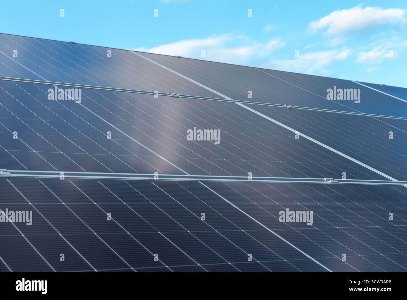 Reihen moderner Photovoltaik-Solarpaneele, die unter hellem Tageslicht erneuerbare Energie erzeugen Stockfoto