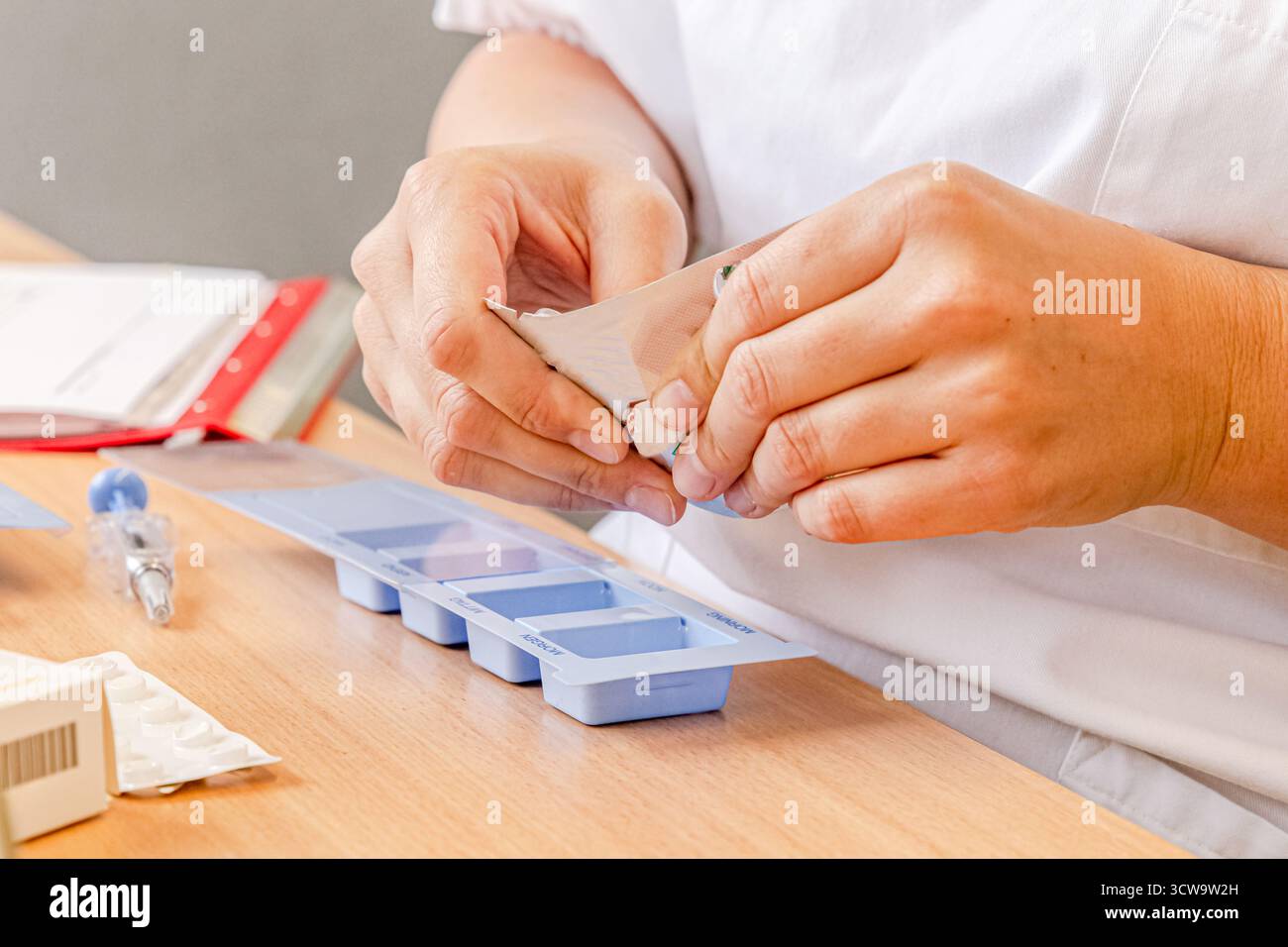 Krankenschwester, die Medikamente in einem wöchentlichen Pillen-Organisator vorbereiten, professionelle medizinische Versorgung und Genauigkeit in der Krankenpflege Stockfoto