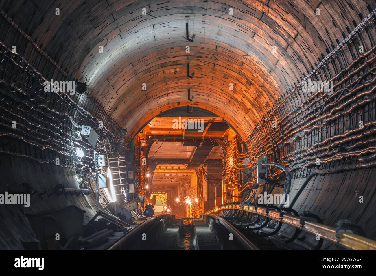Unterirdischer U-Bahn-Tunnel im Bau mit Stahlbetonwänden, technischen Details und industrieller Beleuchtung. Stockfoto