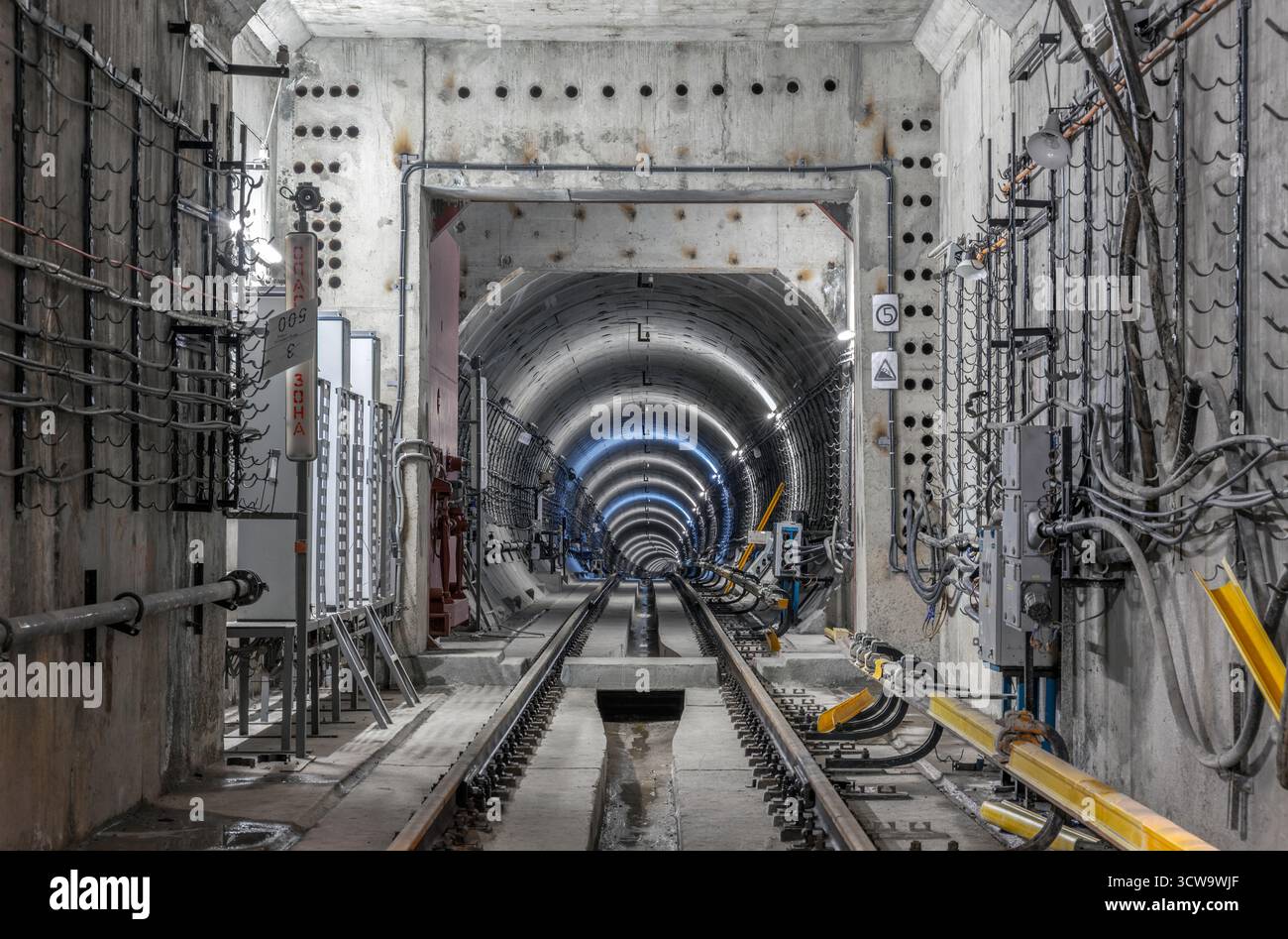 Unterirdischer U-Bahn-Tunnel im Bau mit Stahlbetonwänden, Ingenieurkonstruktionen und dramatischer Industriebeleuchtung. Stockfoto