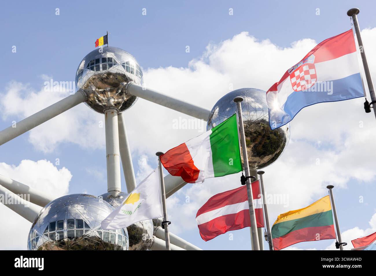 Flaggen mehrerer EU-mitgliedstaaten winken vor dem Atomium in Brüssel, mit der belgischen Flagge oben. Ab dem 12. Oktober 2025 wird das neue Einreise-/Ausreisesystem (EES) die Passabstempelung durch biometrische Registrierung (Fingerabdrücke) für nicht-EU-Reisende – einschließlich Briten – ersetzen. Quelle: Sinai Images/Alamy Live News Stockfoto
