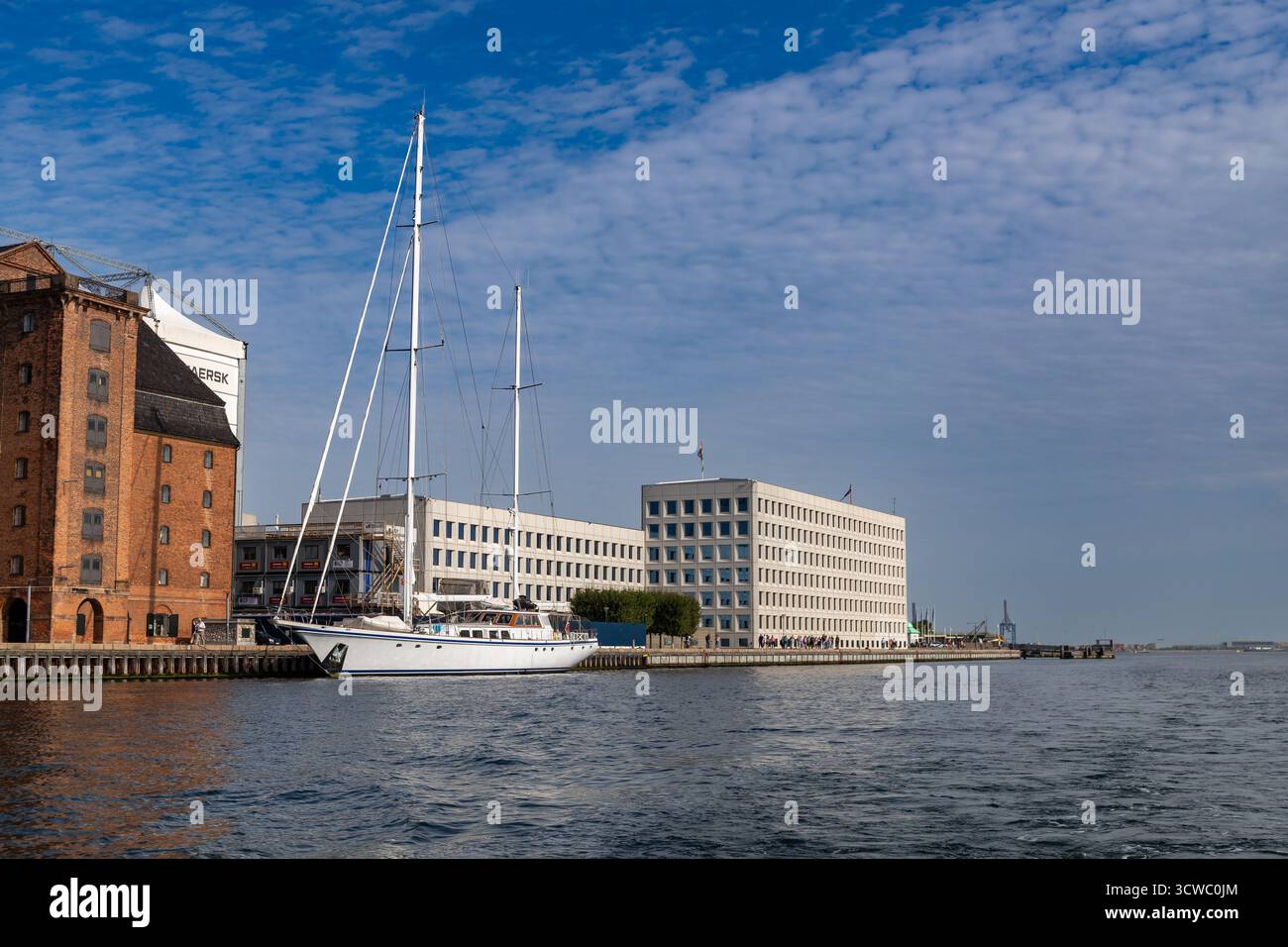 Kopenhagen, Dänemark-14. August 2025: Große weiße Yacht am Kai, neben Maersk Bürogebäude, Backsteinlager und Baucontainer Stockfoto