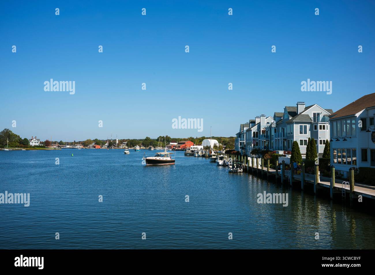 Ein kleines Boot navigiert durch das Wasser des Mystic River in Mystic, CT, in New England, von der Mystic River Bascule Bridge aus gesehen, während eines wunderschönen fa Stockfoto