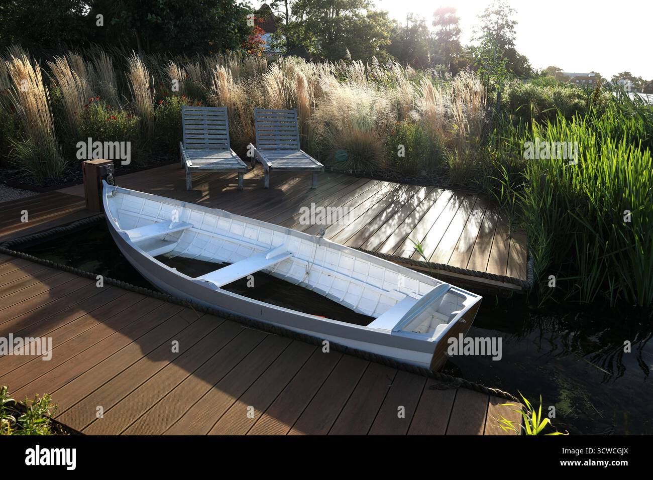 Thorpeness, Suffolk, England, Großbritannien - viele Häuser in der Lakeside Avenue haben einen Garten am Rande des Meare Bootsee, einen eigenen Bootssteg und ein Ruderboot Stockfoto