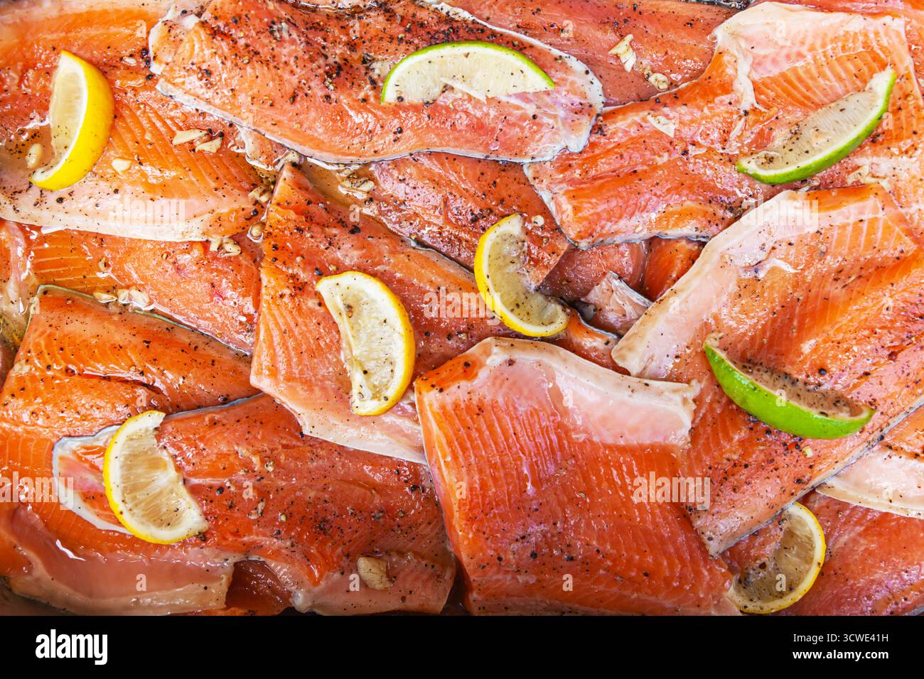 Rote Fischfiletstücke mit Zitronen- und Limettenstücken darauf Stockfoto