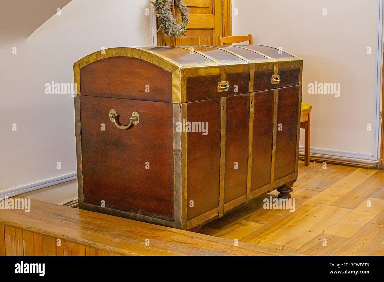 Eine antike Holzkiste mit goldenen Akzenten, die möglicherweise bedeutend sind, ist auf einer Bühne oder einem Podium ausgestellt. Sie hat ein luxuriöses und historisches Flair und macht sie zu einem echten Stockfoto