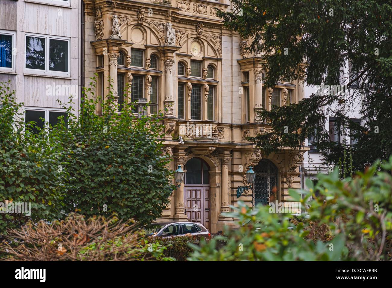 Ein kunstvoll verziertes, historisches Gebäude in Düsseldorf steht zwischen modernen Bauten und zeigt komplexe architektonische Details Stockfoto