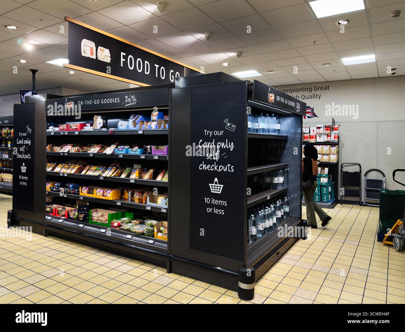 Manchester, Großbritannien - 26. September 2025: Moderne Aldi-Supermarktszene mit Selbstkauf und „Food to Go“-Schildern, Einkäufer, die Snacks und Getränke suchen. Stockfoto
