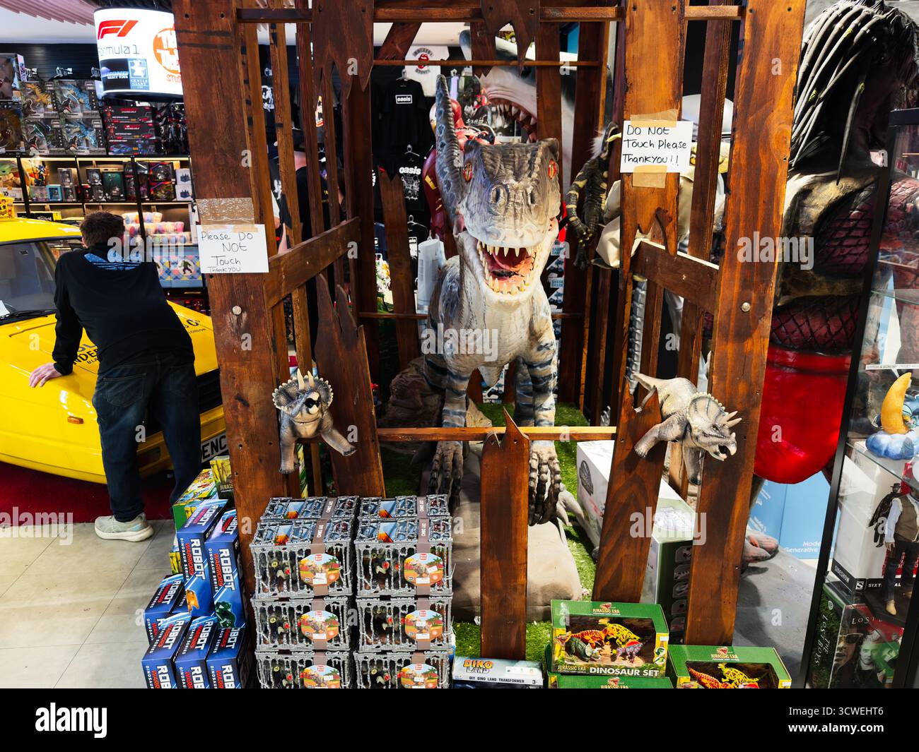 Manchester, Großbritannien – 26. September 2025: Spielzeugladen mit einer lebensgroßen Dinosaurierstatue in einem Holzrahmen mit Schildern und farbenfrohen Waren. Stockfoto