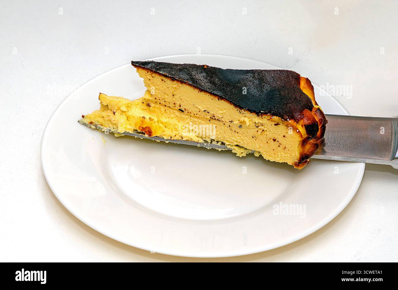 Baskisches Käsekuchen-Dessert-Stück auf Keramikplatte Stockfoto