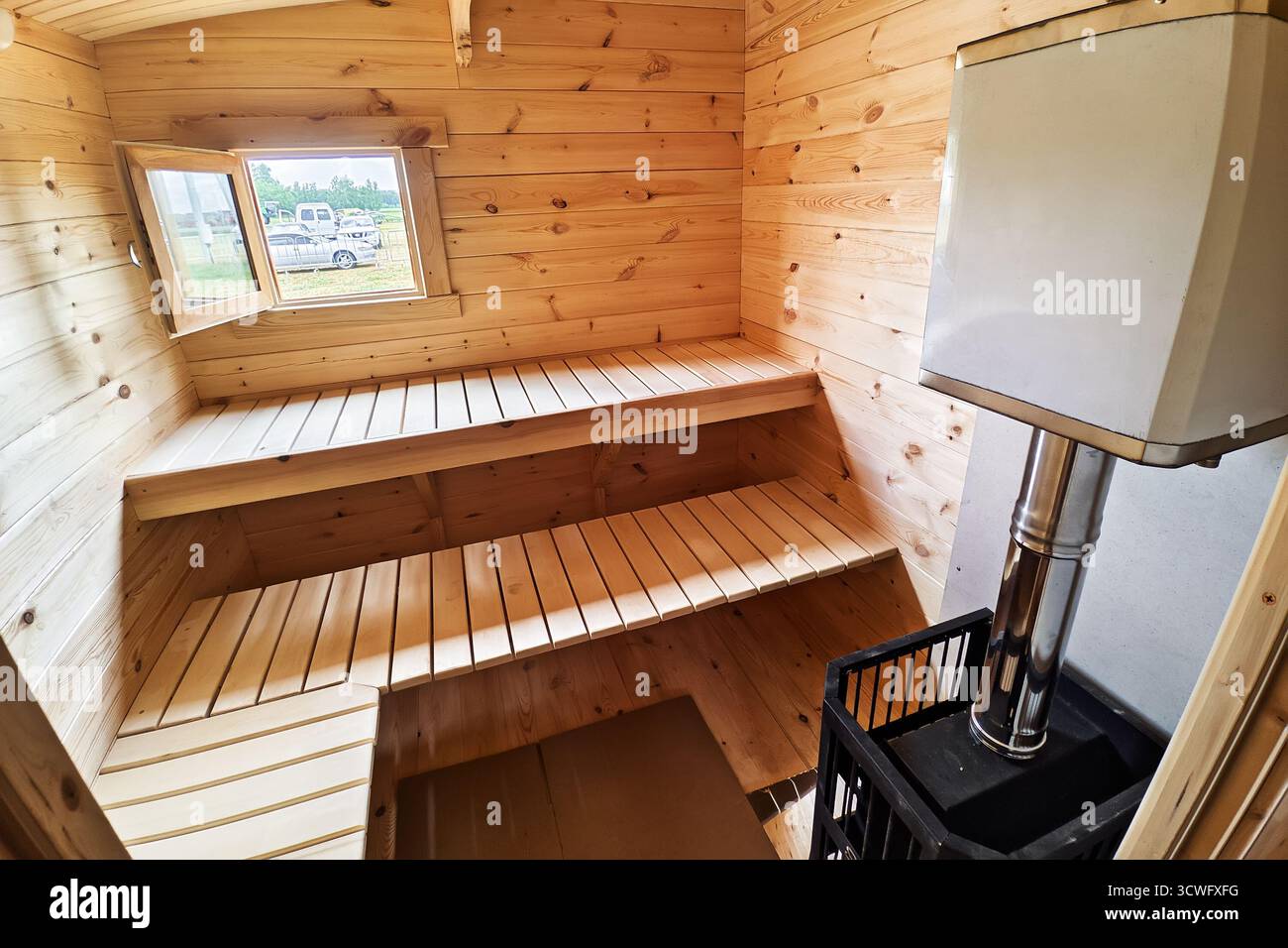 Sitzplatz im Saunabereich. Leeres hölzernes Dampfbad mit Steinheizung. Sauna für gute Gesundheit. Saunabereich mit traditionellem Saunazubehör. Gesund und Stockfoto