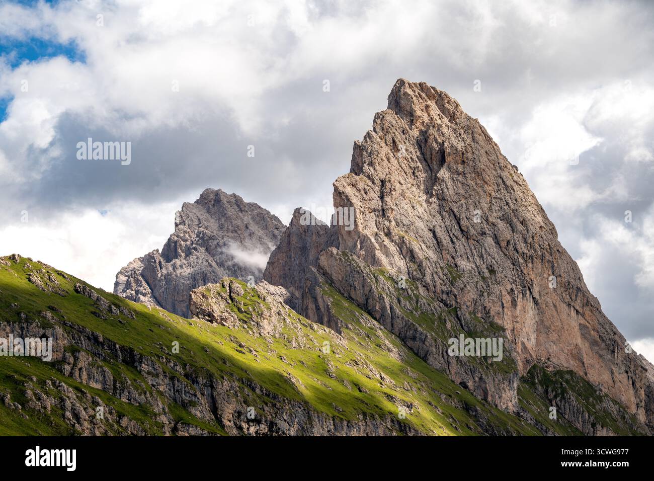 Dramatischer Gipfel von Gran Fermeda und Sass Rigais, der sich in Gröden in den italienischen Dolomiten scharf gegen einen teilweise bewölkten Himmel erhebt Stockfoto