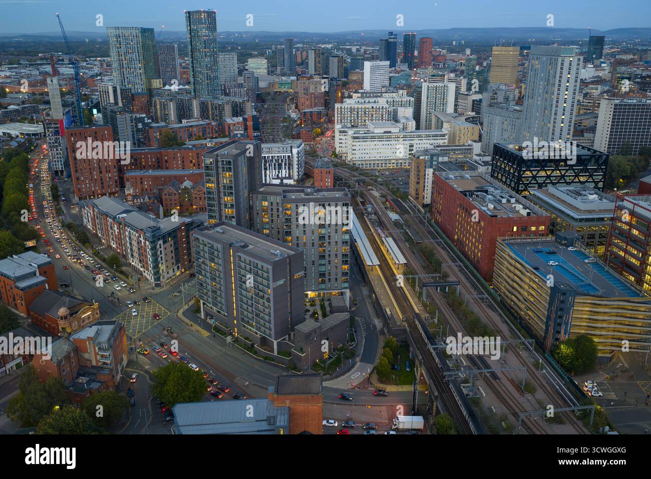 Blick aus der Vogelperspektive über dem Hauptbahnhof Salford mit Blick auf Greengate und das Stadtzentrum von Manchester in der Abenddämmerung Stockfoto