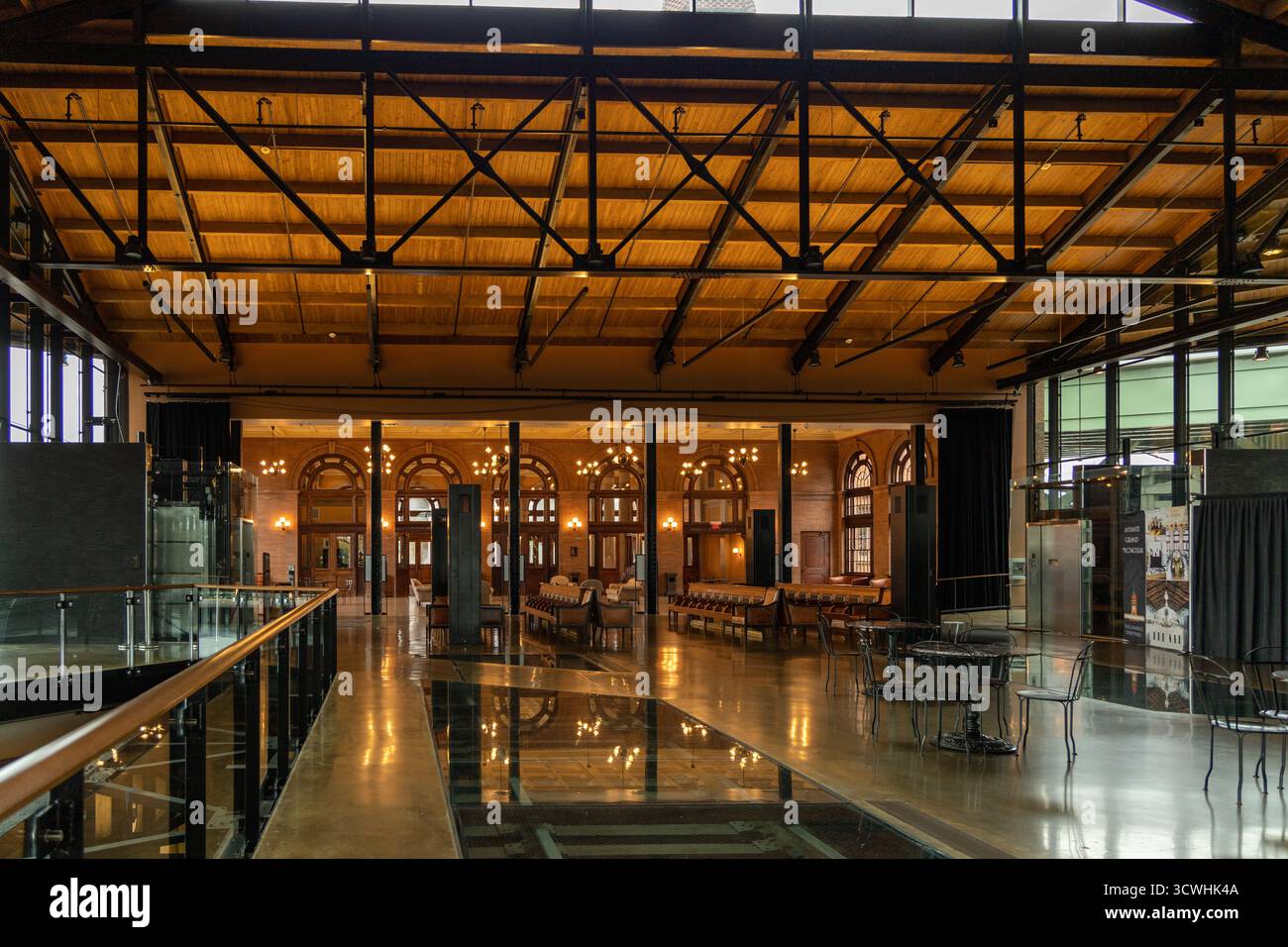 Ein großes, leeres Gebäude mit viel Licht durch die Fenster. Das Gebäude scheint ein großer, offener Raum mit vielen Sitzgelegenheiten und Tischen zu sein Stockfoto