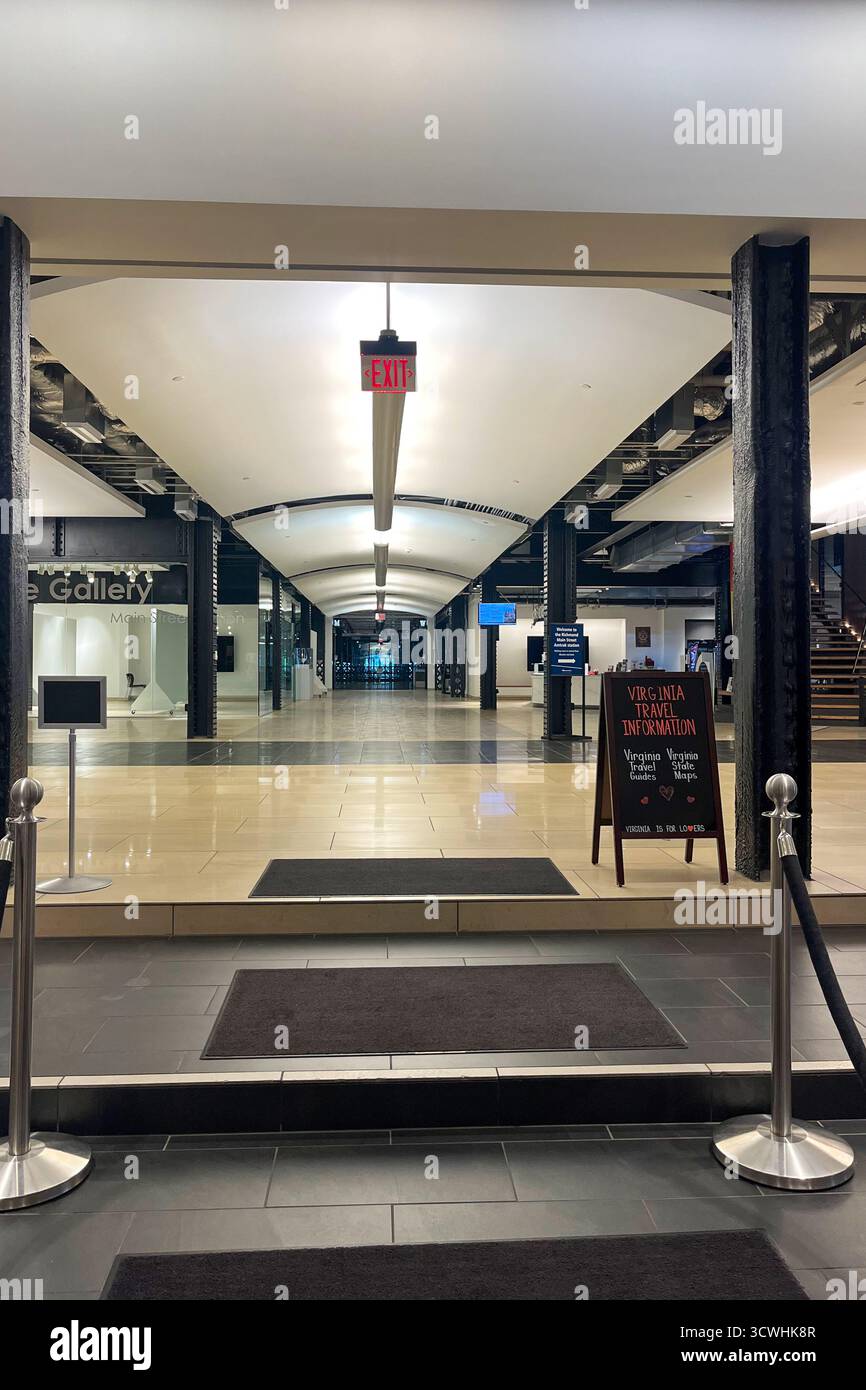 Ein großer, leerer Flur mit einem Schild mit der Aufschrift 'Exit' darüber. Der Flur ist von Lichtern beleuchtet und hat einen schwarzen Teppich, Hauptbahnhof. Richmo Stockfoto