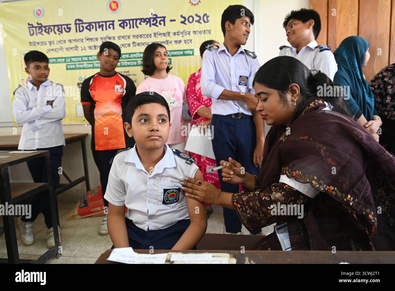 Ein Schüler erhält während einer nationalen Impfkampagne in Dhaka, Bangladesch, am 12. Oktober 2025 einen Typhus-Impfstoff in einem Schulimpfzentrum. Zum ersten Mal hat die Regierung damit begonnen, Typhus im ganzen Land zu impfen. Etwa 50 Millionen Kinder im Alter von 9 Monaten bis 15 Jahren erhalten den Impfstoff über 18 Arbeitstage kostenlos. Die ersten 10 Arbeitstage werden in verschiedenen Schulen und die nächsten acht Arbeitstage in Impfzentren gegeben. Stockfoto