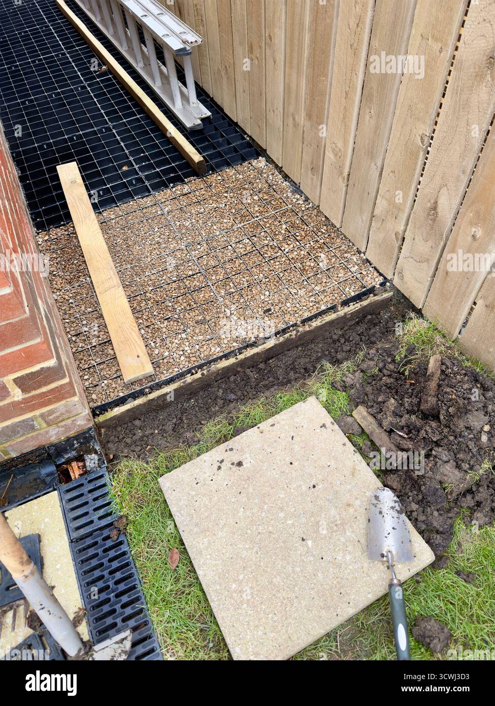 Baustelle mit verlegtem Kies und Pflastern, neben einem Holzzaun, die ein Bauprojekt im Bau zeigt - Smartphone-aufgenommenes Stockfoto