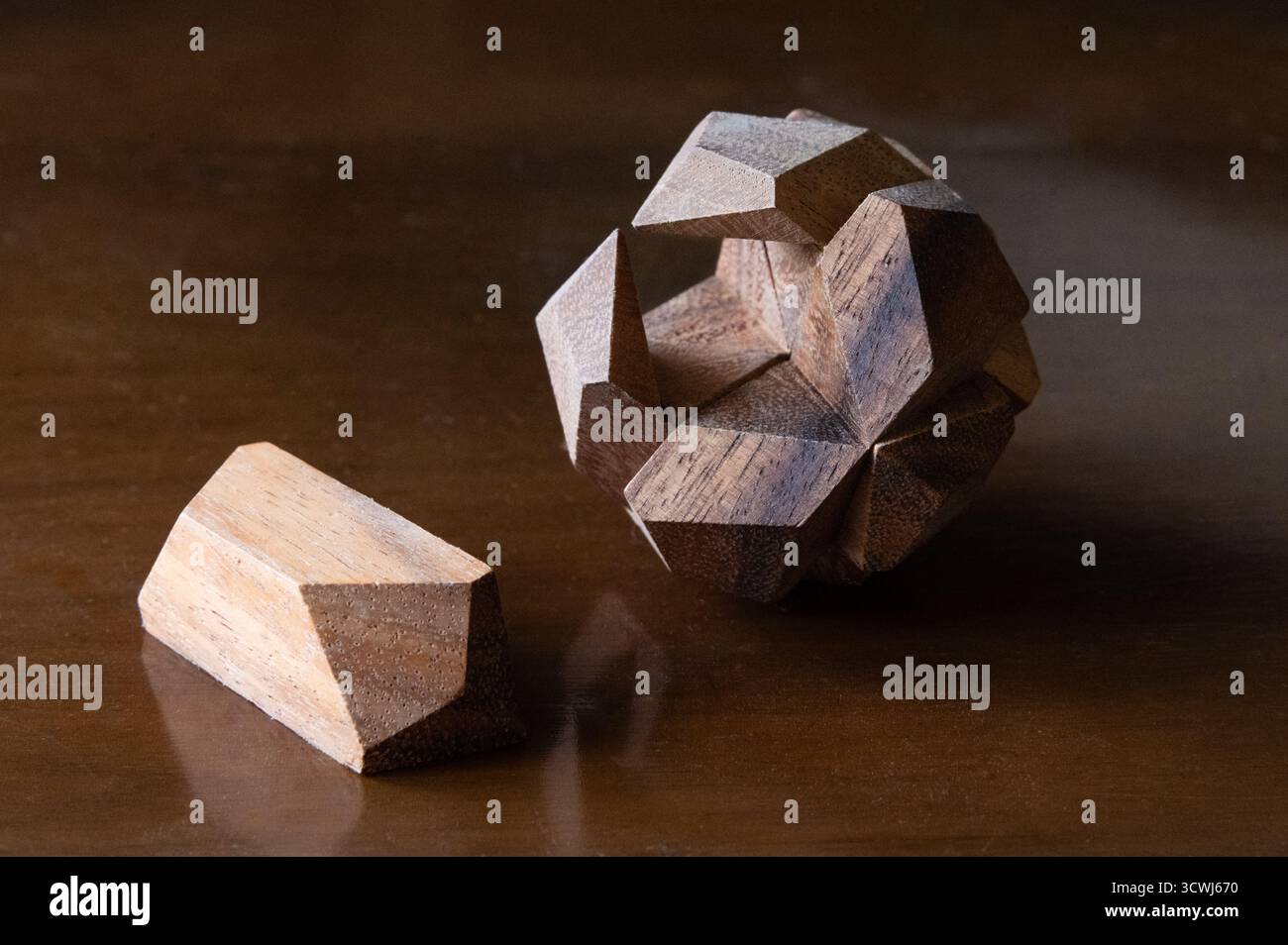 Eine hölzerne Puzzlekugel mit einem Stück aus dem Platz auf einem Holztisch Stockfoto