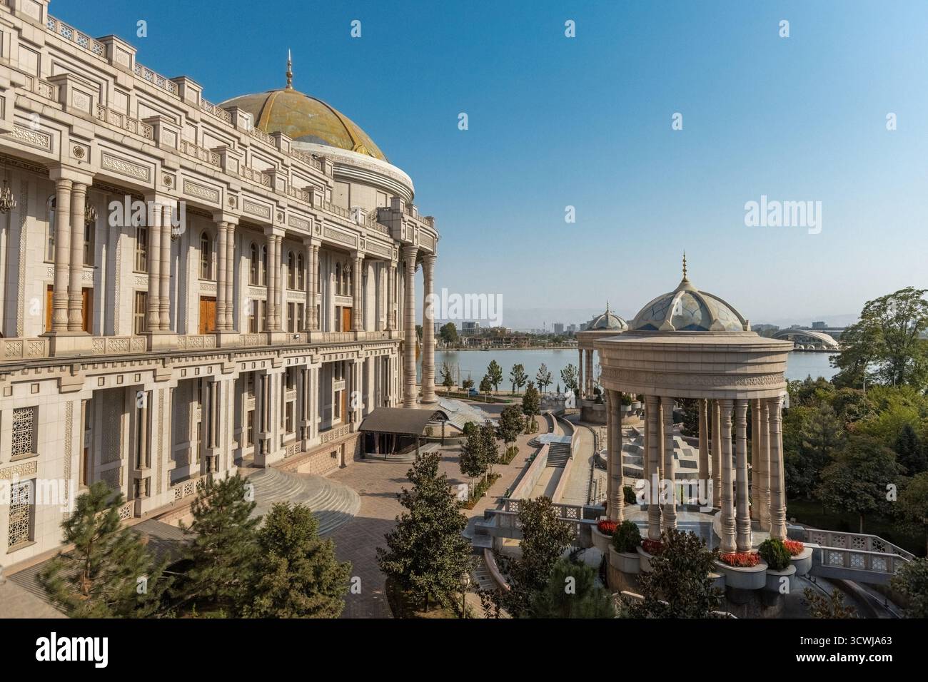 Majestätischer Blick auf den Navruz-Palast in Duschanbe, Tadschikistan, mit großen Säulen, Kuppelpavillons und einer malerischen Seenlandschaft unter einem klaren blauen Stockfoto