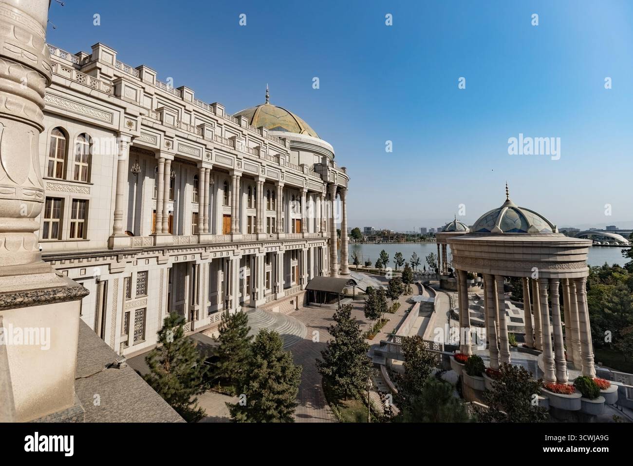 Majestätischer Blick auf den Navruz-Palast in Duschanbe, Tadschikistan, mit großen Säulen, Kuppelpavillons und einer malerischen Seenlandschaft unter einem klaren blauen Stockfoto