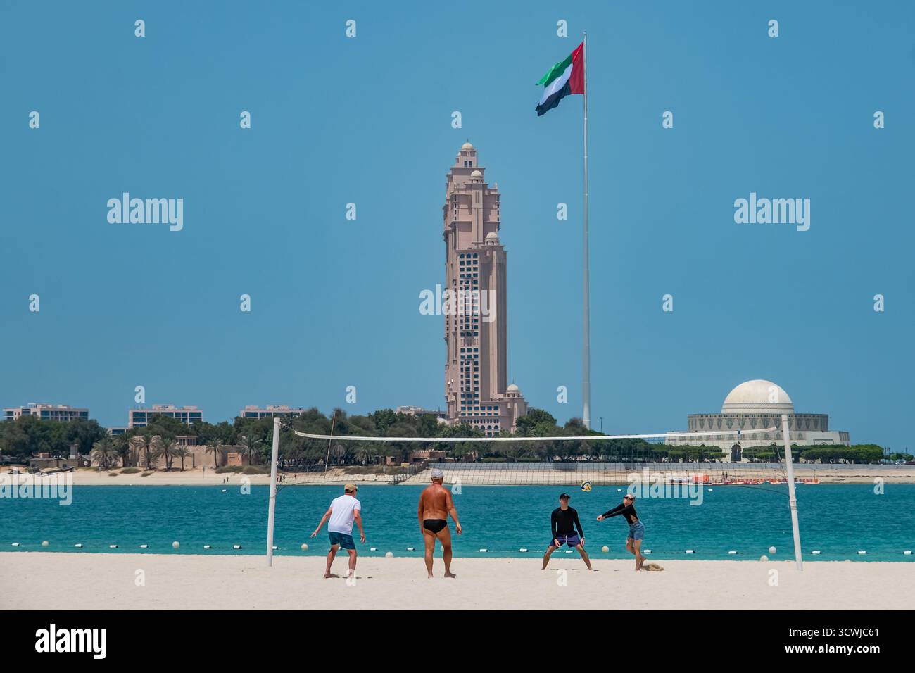 Leute spielen Volleyball an einem Sandstrand in Abu Dhabi. Corniche Beachfront mit Blick auf Marina Mall und Rixos Marina Hotel Abu Dhabi VAE. Reise-Pho Stockfoto