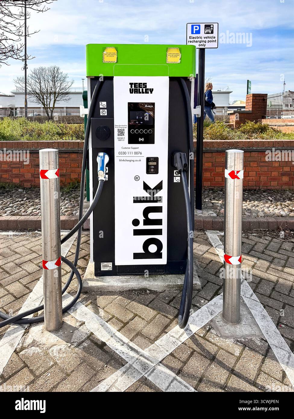 Ladestation für Elektrofahrzeuge mit Blink-Branding auf einem Parkplatz, mit Ladestation und Umgebung. - Smartphone-aufgenommenes Stockfoto