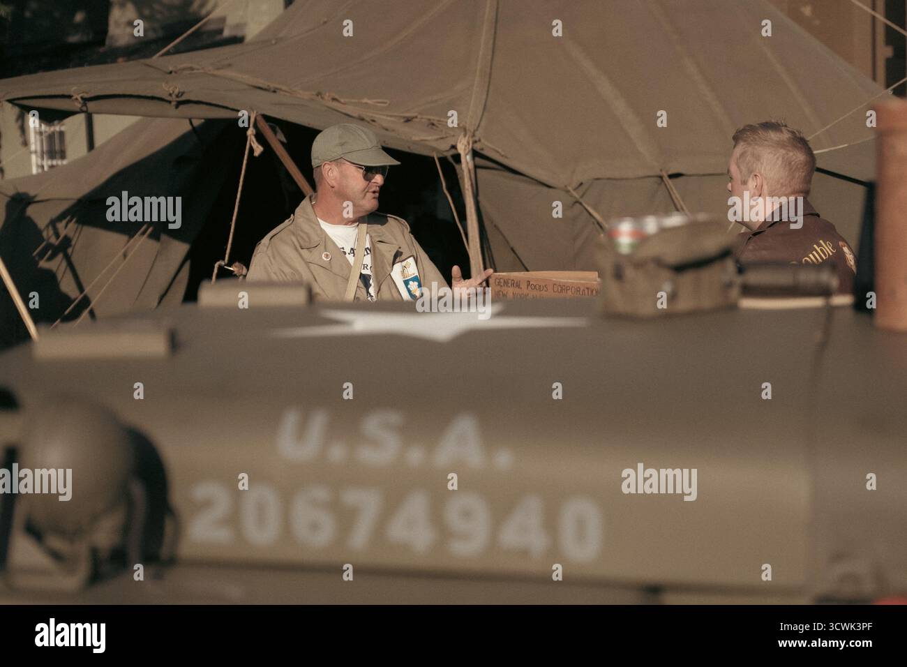 Wiederinszenierungen aus dem Zweiten Weltkrieg in Militäruniformen, die sich neben dem alten US-Army-Jeep auf dem historischen Flugplatz unterhalten Stockfoto