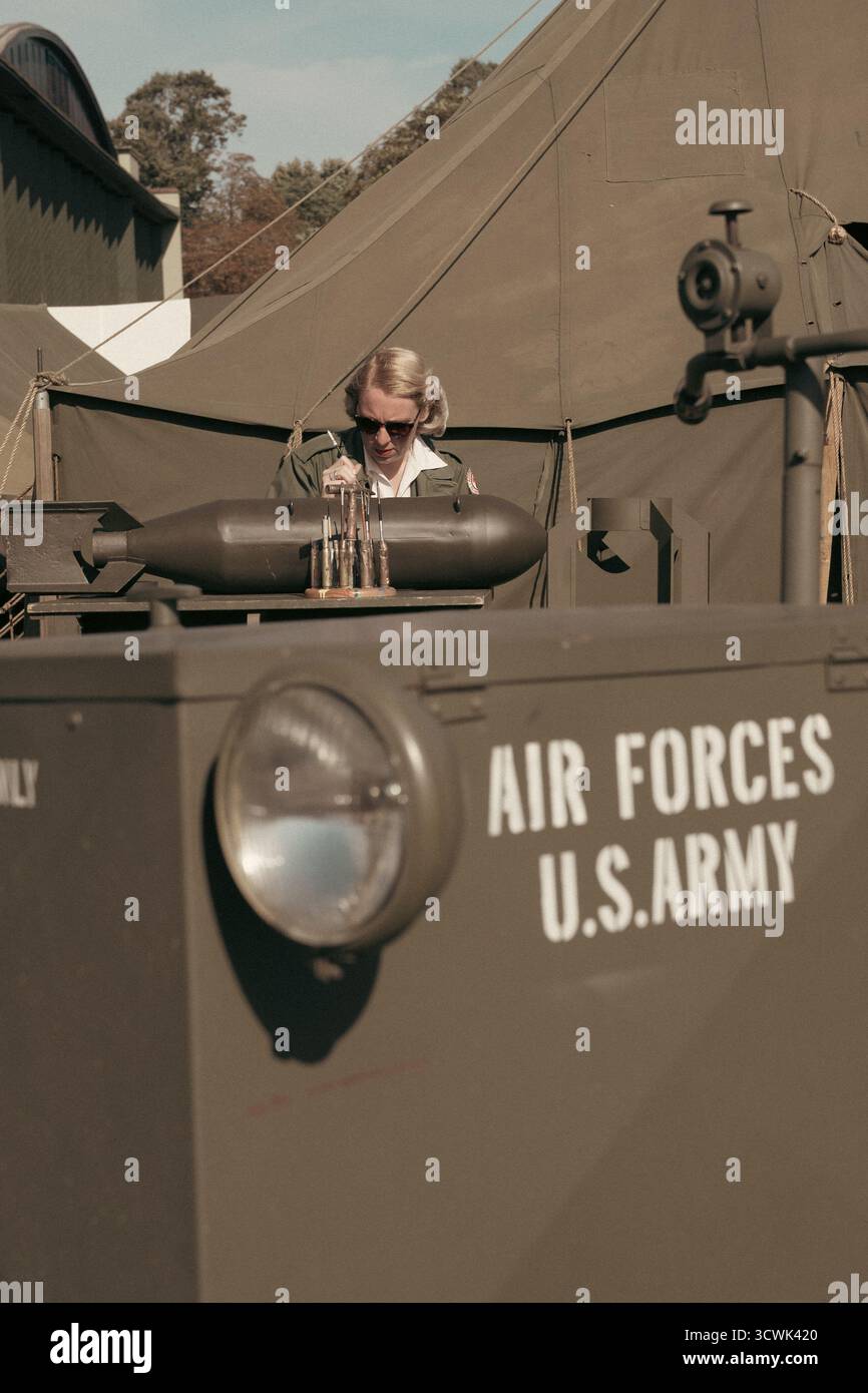 Eine Frau in zeitlicher Uniform, die ein klassisches Militärfahrzeug der US Army Air Forces in Duxford betreibt Stockfoto