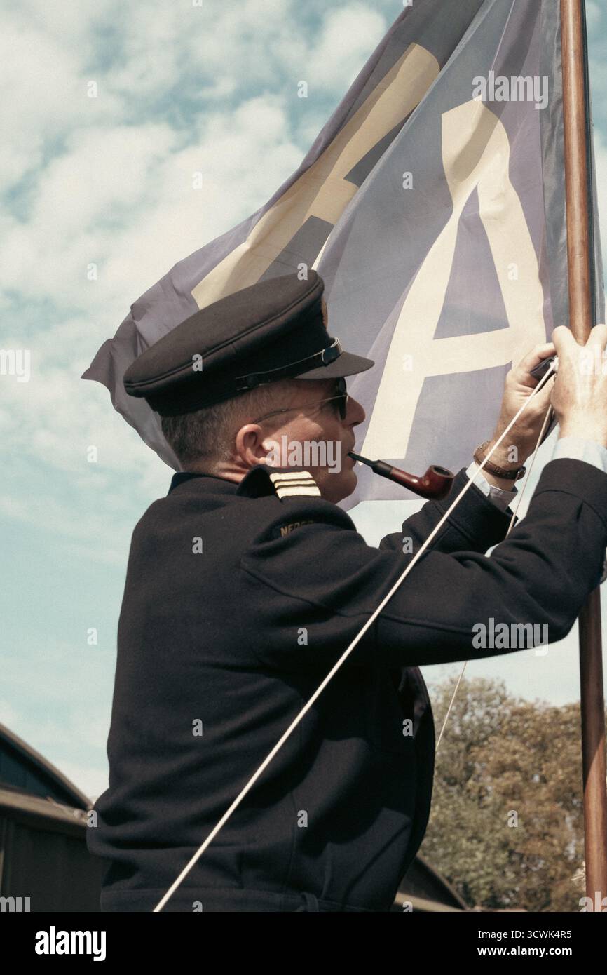 RAF-Offizier hisst Fähnchenflagge bei der Gedenkfeier des Flugplatzes Duxford Stockfoto