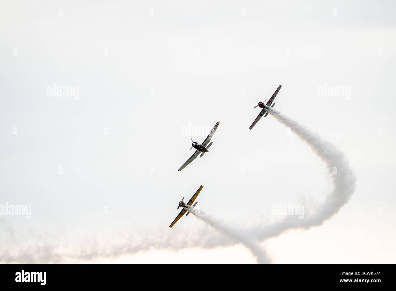 Drei Flugzeuge, die Kunstflugzeuge mit weißen Rauchspuren vor bewölktem Himmel zeigen Stockfoto