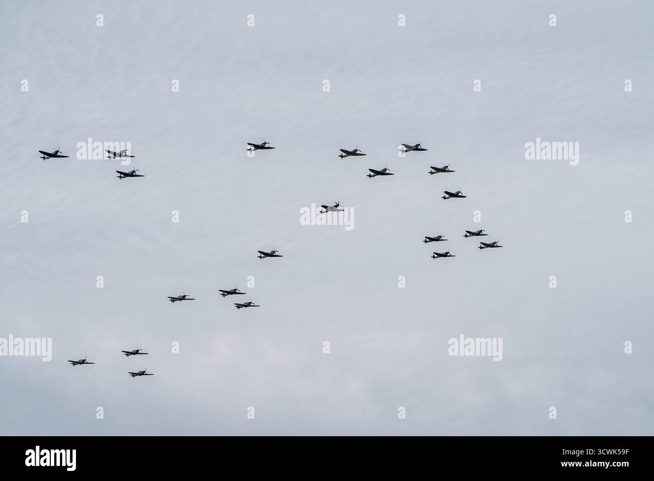 Große Formation von Militärflugzeugen, die bei bewölktem Himmel auf der Duxford Airshow fliegen Stockfoto