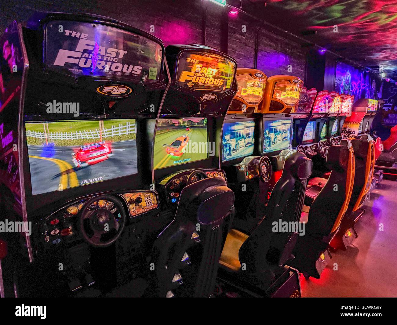 Die Spielautomaten Fast und The Furious stehen in einem neonbeleuchteten Retro-Spielort Stockfoto