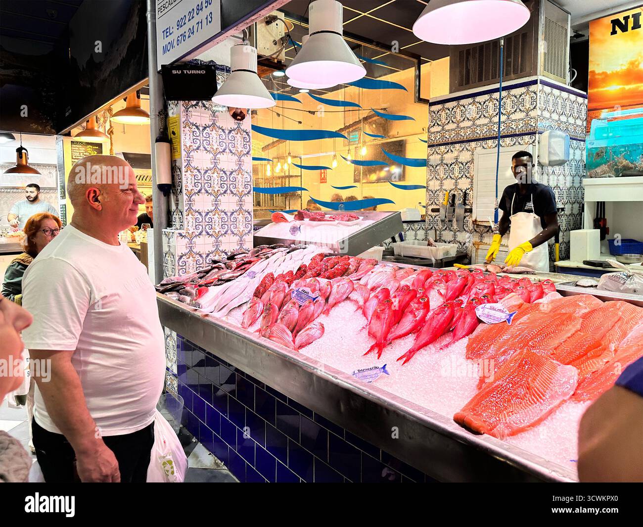 Gäste stöbern in einem lebhaften Fischmarkt mit farbenfrohen Ausstellungen und aufmerksamem Personal durch eine große Auswahl an frischem Fisch.Teneriffa Kanarischen Inseln Stockfoto