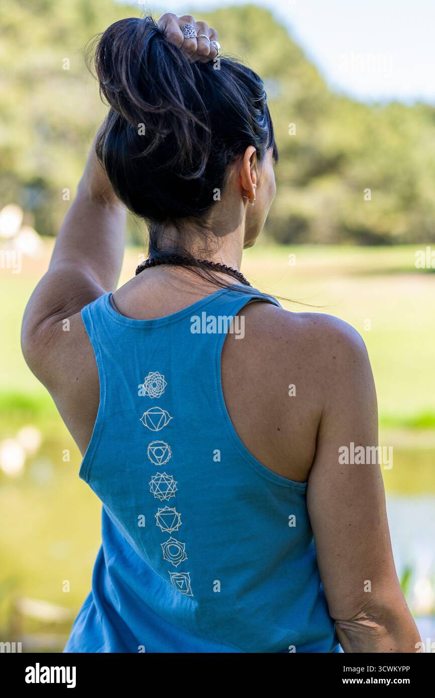 Frau, die draußen Chakra-Symbole auf ihrem Tanktop zeigt. Stockfoto