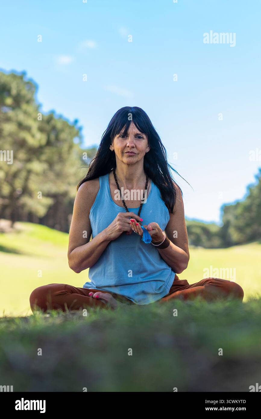 Frau, die geistiges und körperliches Wohlbefinden durch Meditation an Bäumen sucht. Stockfoto