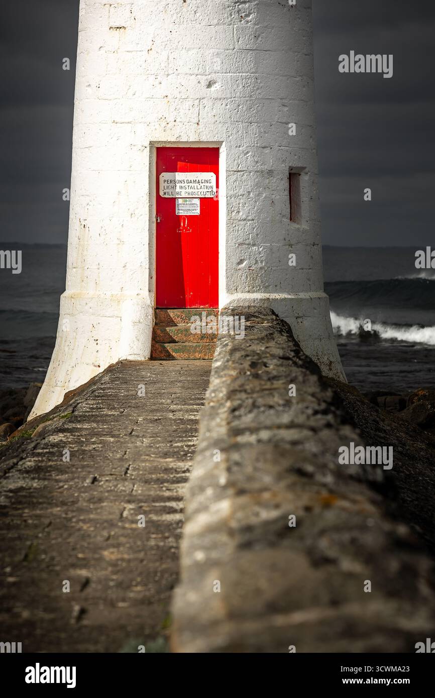 Weißer Leuchtturm mit leuchtender roter Tür auf Griffith Island an der Küste von Port Fairy, Victoria, Australien. Stockfoto