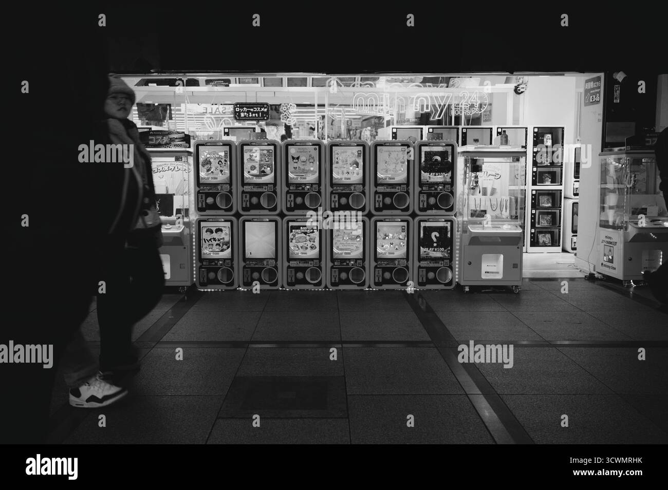 Hell beleuchtete Reihe von Gashapon-Maschinen und ein Klauenspiel in einer Osaka-Arkade in Schwarz-weiß Stockfoto