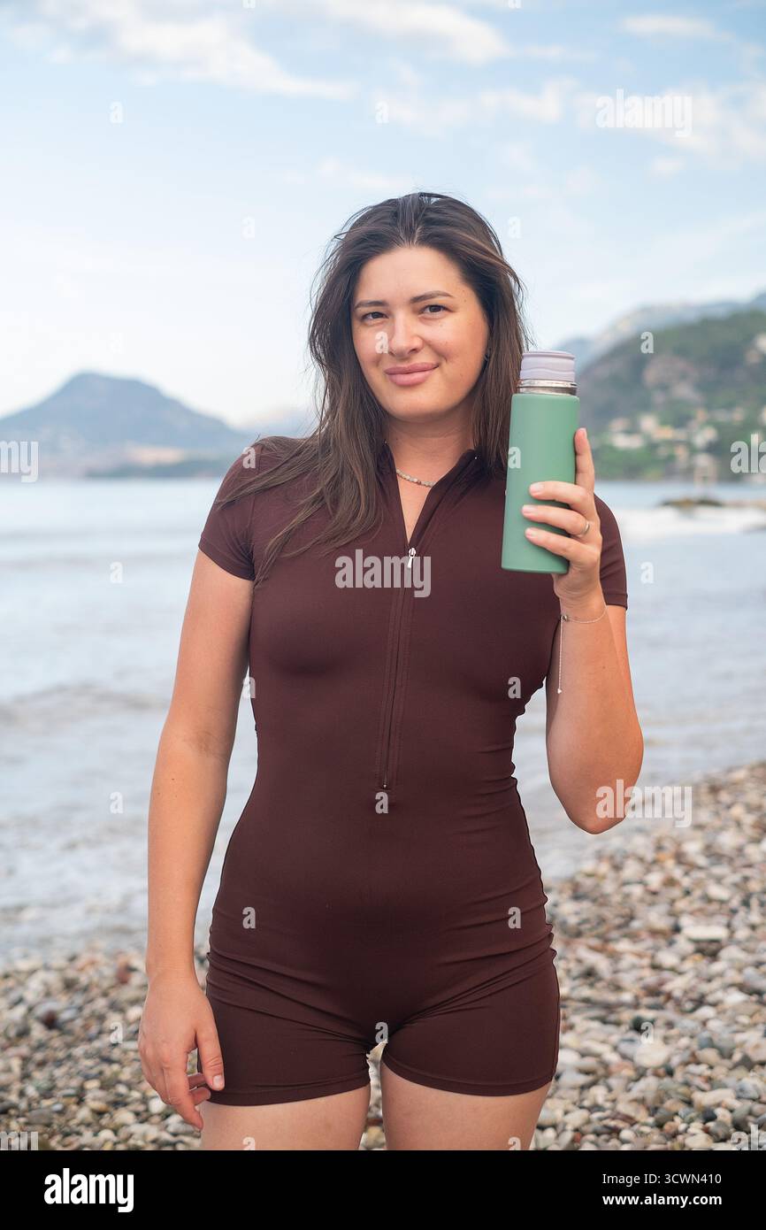 Junge Frau trinkt Wasser nach intensivem Training am Strand Outdoor Fitness und gesunder Lebensstil Szene Stockfoto