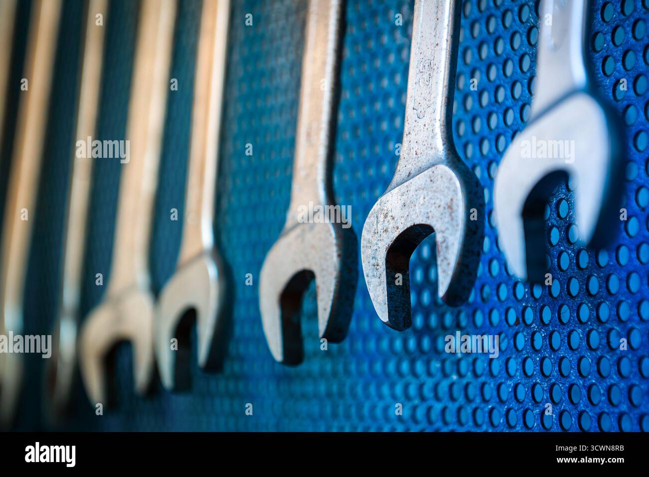 Metallschlüssel auf einer blauen Lochplatte, bereit für Reparaturarbeiten Stockfoto