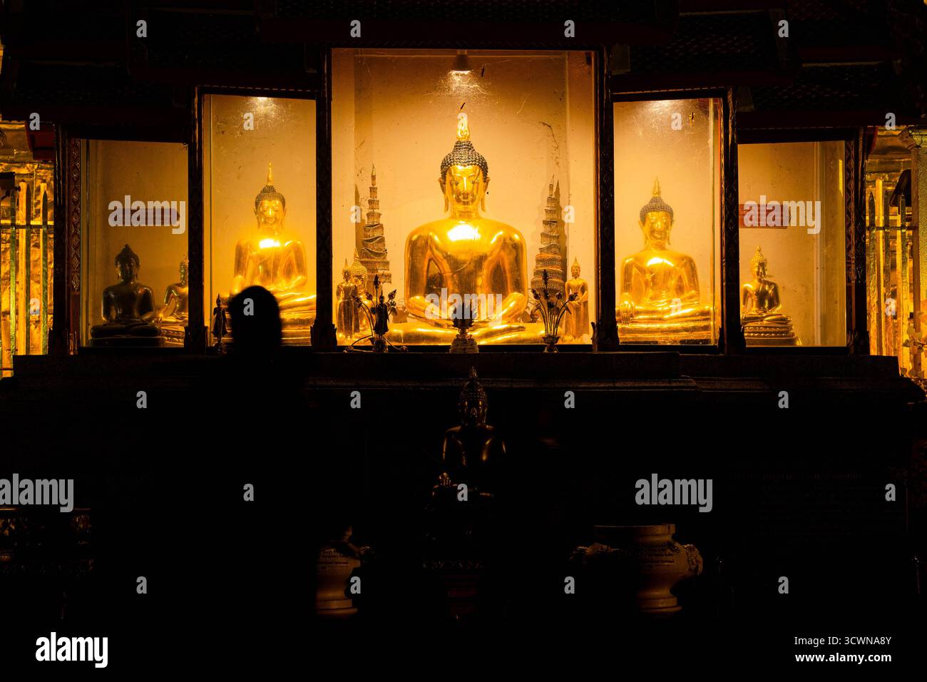 Goldene Buddha-Statuen, beleuchtet bei Nacht in einem thailändischen Tempel, symbolisiert Frieden, Glauben und spirituelle Hingabe im Buddhismus und der thailändischen Kultur. Stockfoto