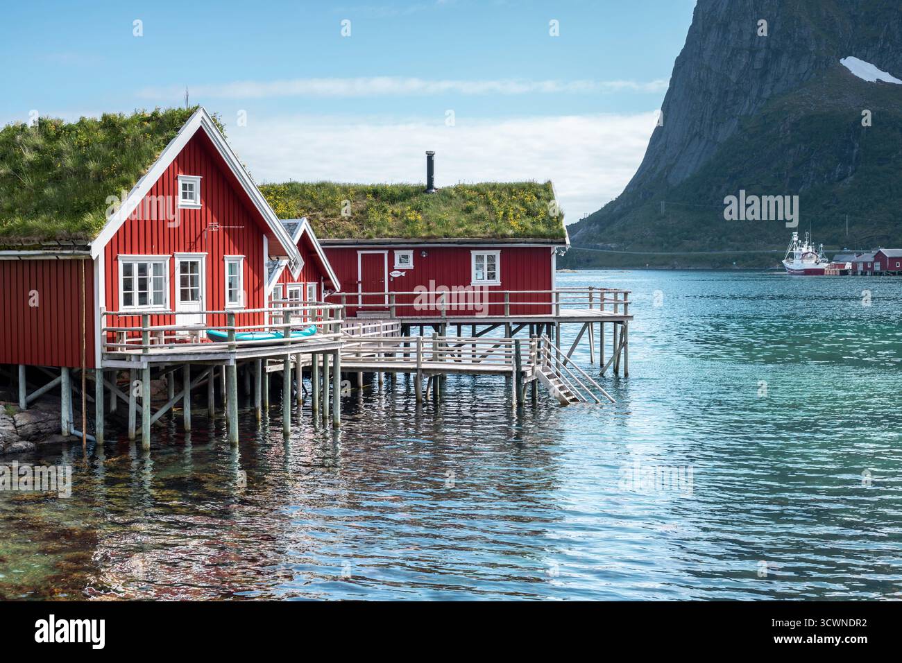 Traditionelle rote Angelhütte (rorbu) auf Stelzen über klarem türkisfarbenem Wasser im Dorf reine, Lofoten, Norwegen. Stockfoto