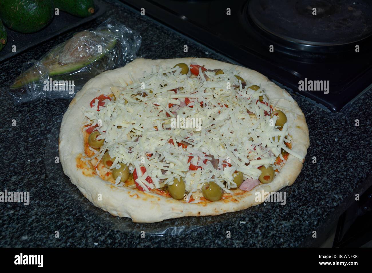 Pizza - einfache Margherita-Basis mit einer Reihe von Extras wie Oliven, Sardellen, Käse usw., die kurz vor dem Kochen stehen. Lecker! Stockfoto