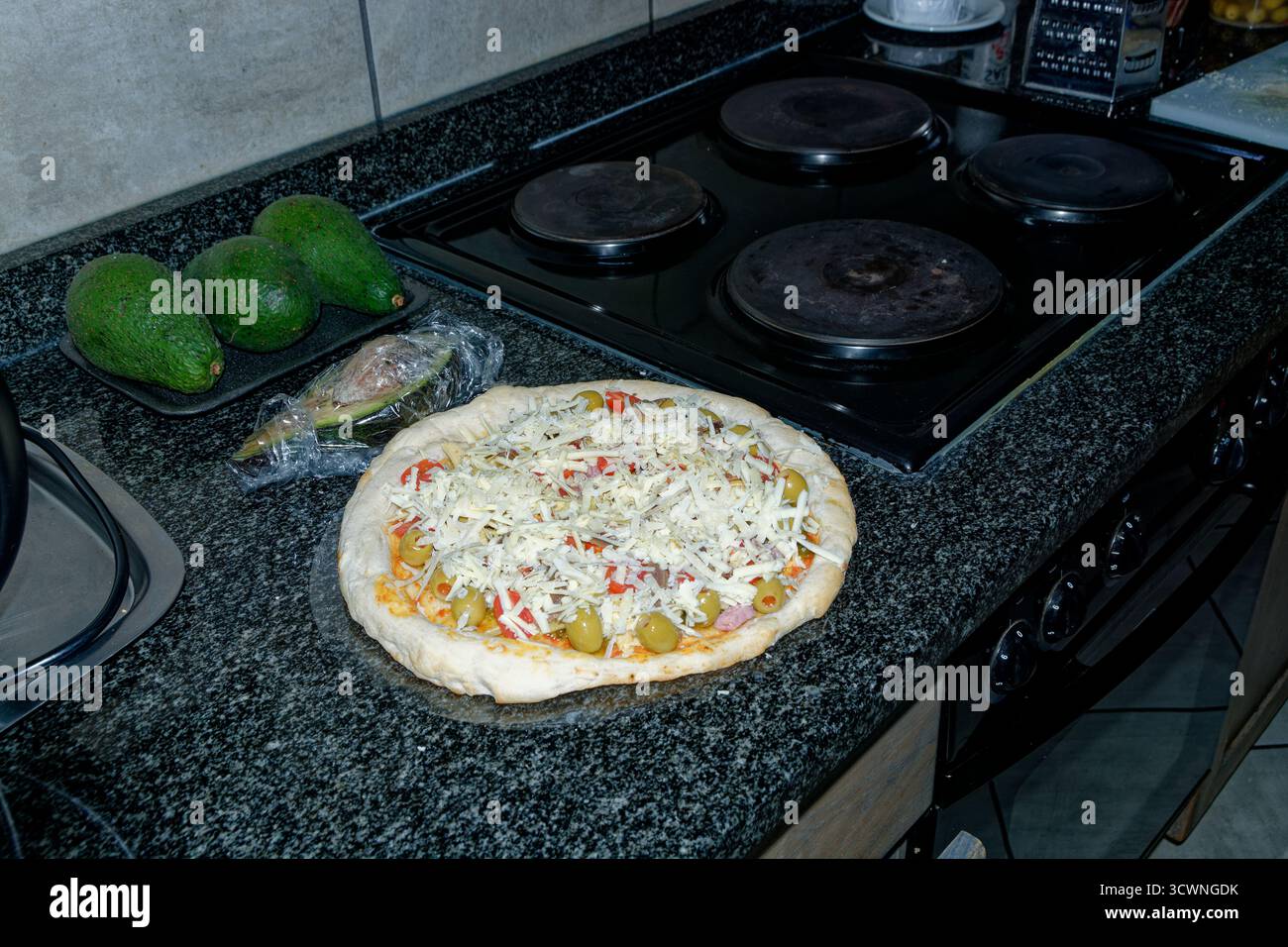 Pizza: Eine margherita-Basis mit zusätzlichen Zutaten, die fertig zum Kochen mit geriebenem Käse hinzugefügt werden. Stockfoto