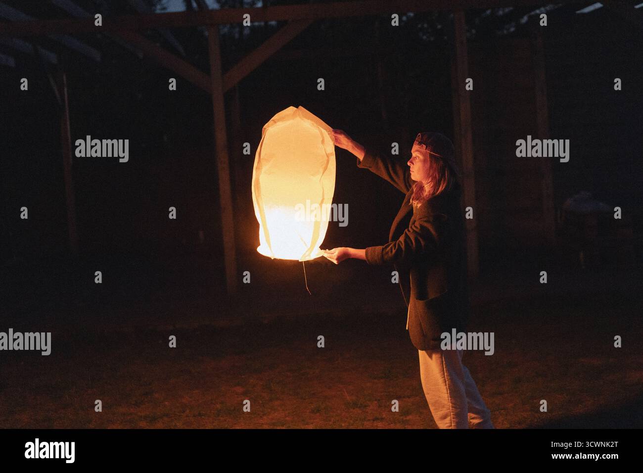 Frau, die nachts eine leuchtende chinesische Himmelslaterne freisetzt Stockfoto