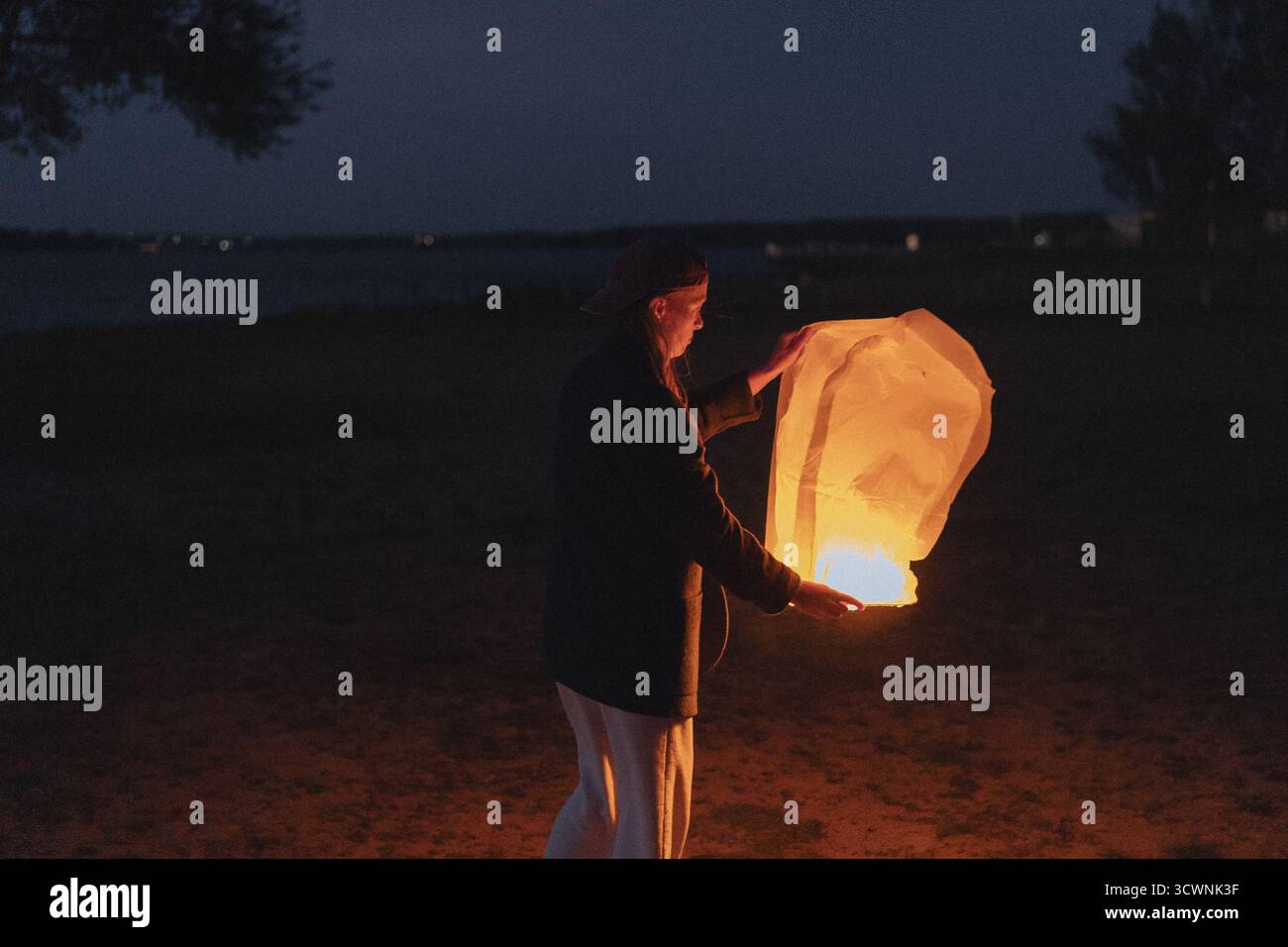 Frau, die nachts eine leuchtende chinesische Himmelslaterne freisetzt Stockfoto
