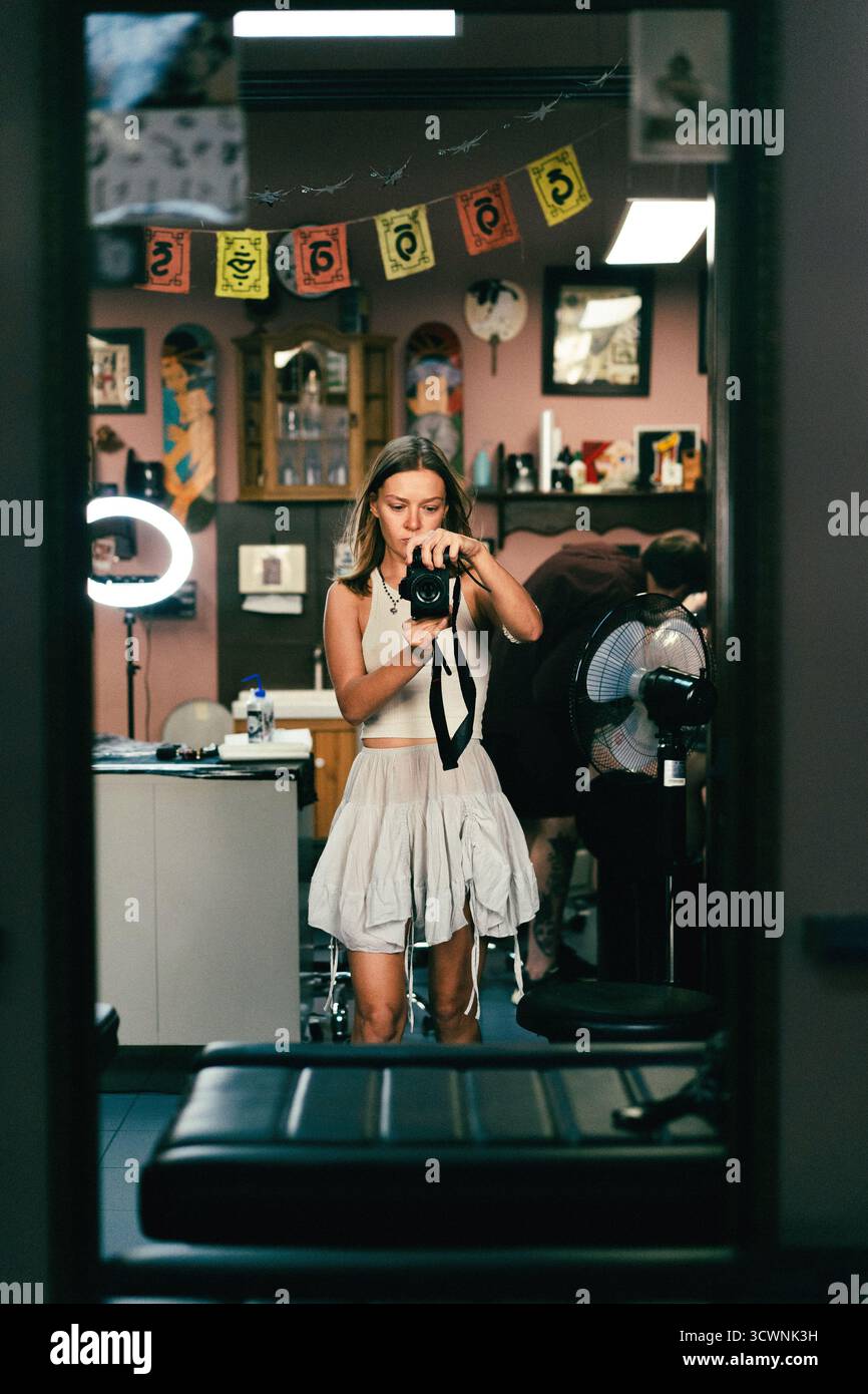 Porträt einer Frau, die eine Kamera in einem Tätowierstudio hält Stockfoto