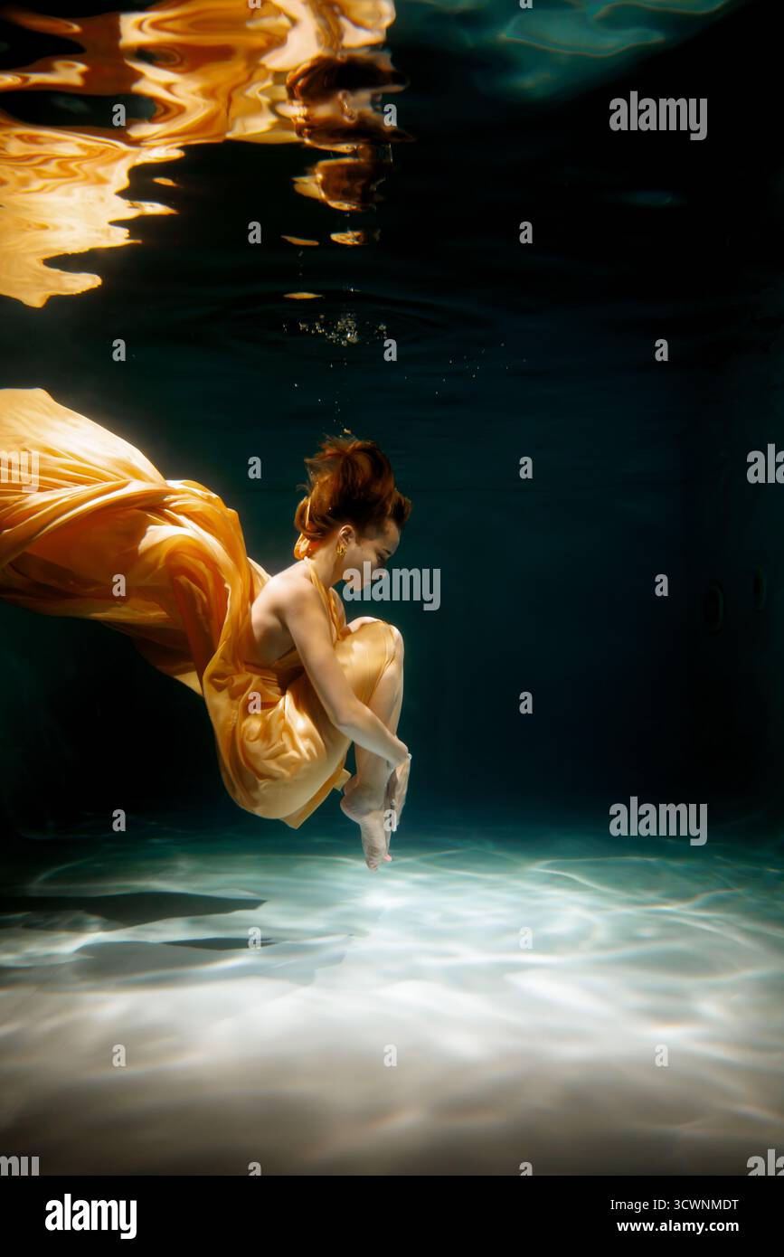 Tänzerin in einem fließenden Kleid, anmutig in Wasser getaucht Stockfoto